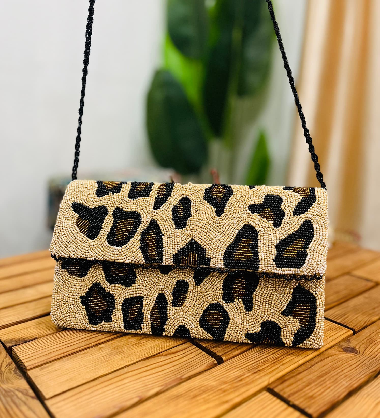 Leopard print envelope clutch with intricate hand-beaded details, showcasing Zara Label branding on front.