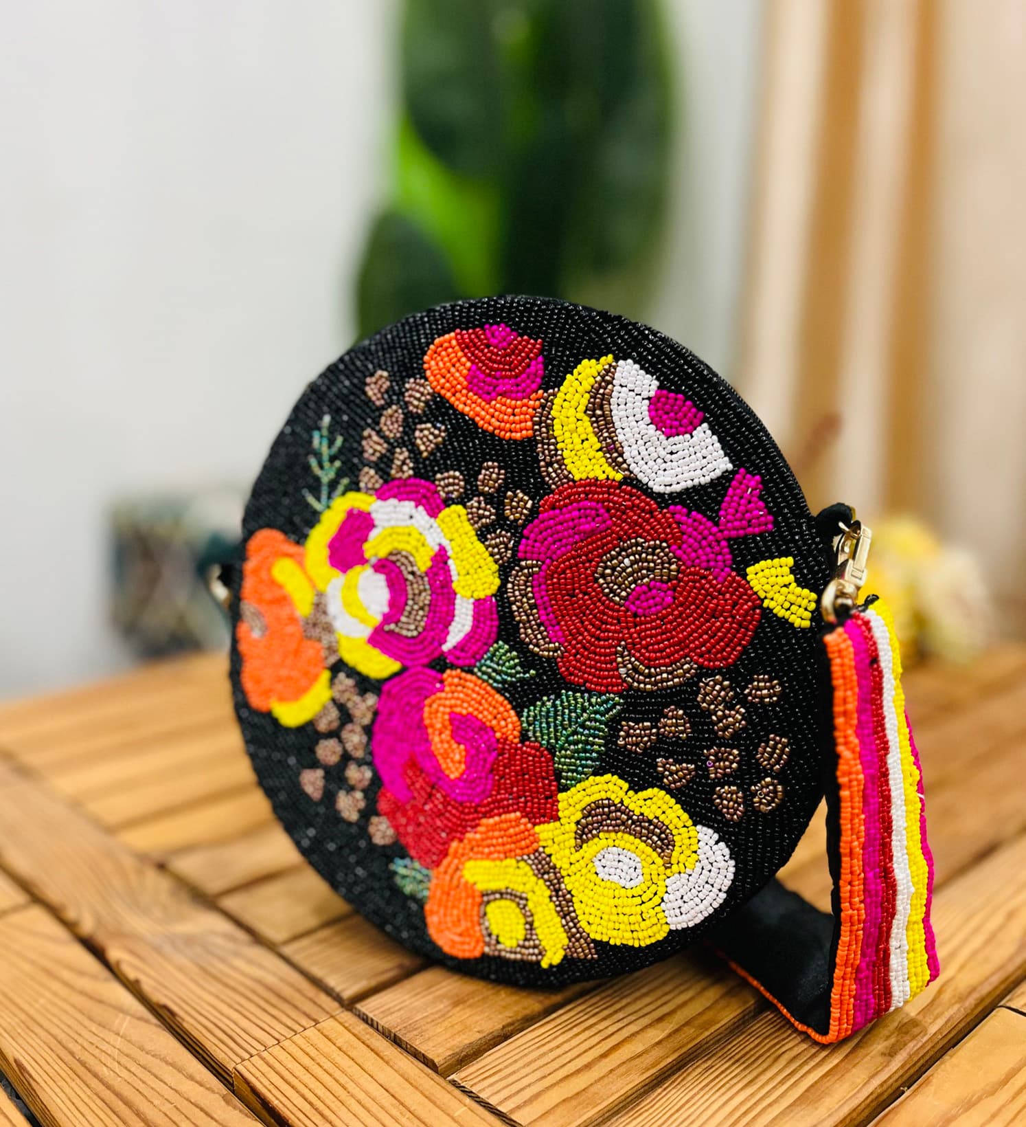 A circular hand-beaded shoulder bag with intricate floral designs in vibrant colors, on a neutral background.