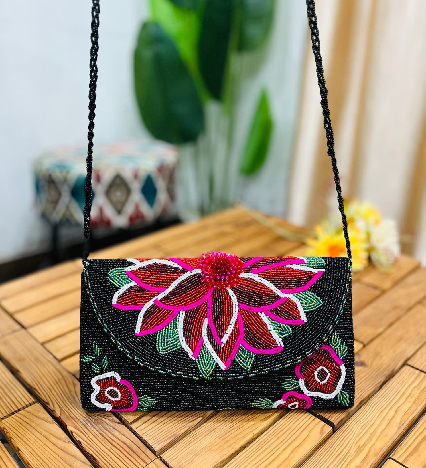 A clutch with intricate floral beadwork in vibrant colors on a midnight blue background, featuring a flap closure with a