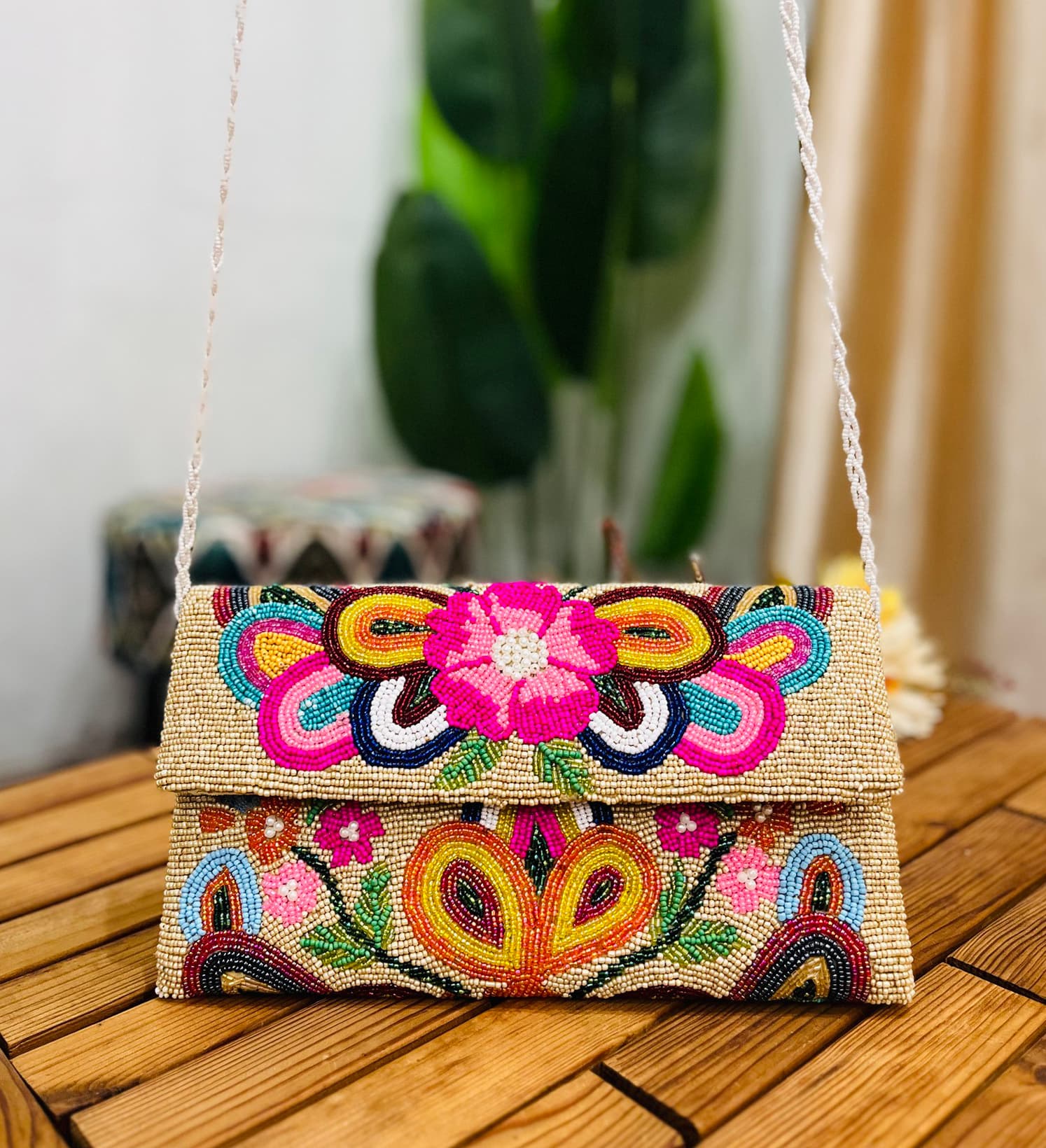 A colorful, hand-beaded envelope clutch with intricate floral patterns, marked with a Zara label, displayed against a