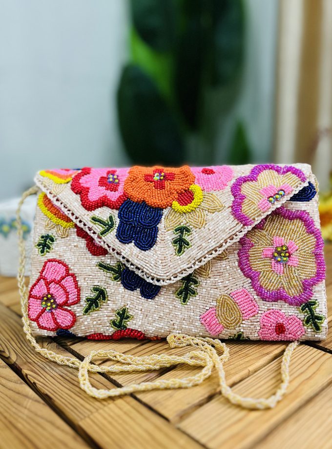 A colorful hand-beaded clutch with floral blossom patterns, made by Zara, on a white background.