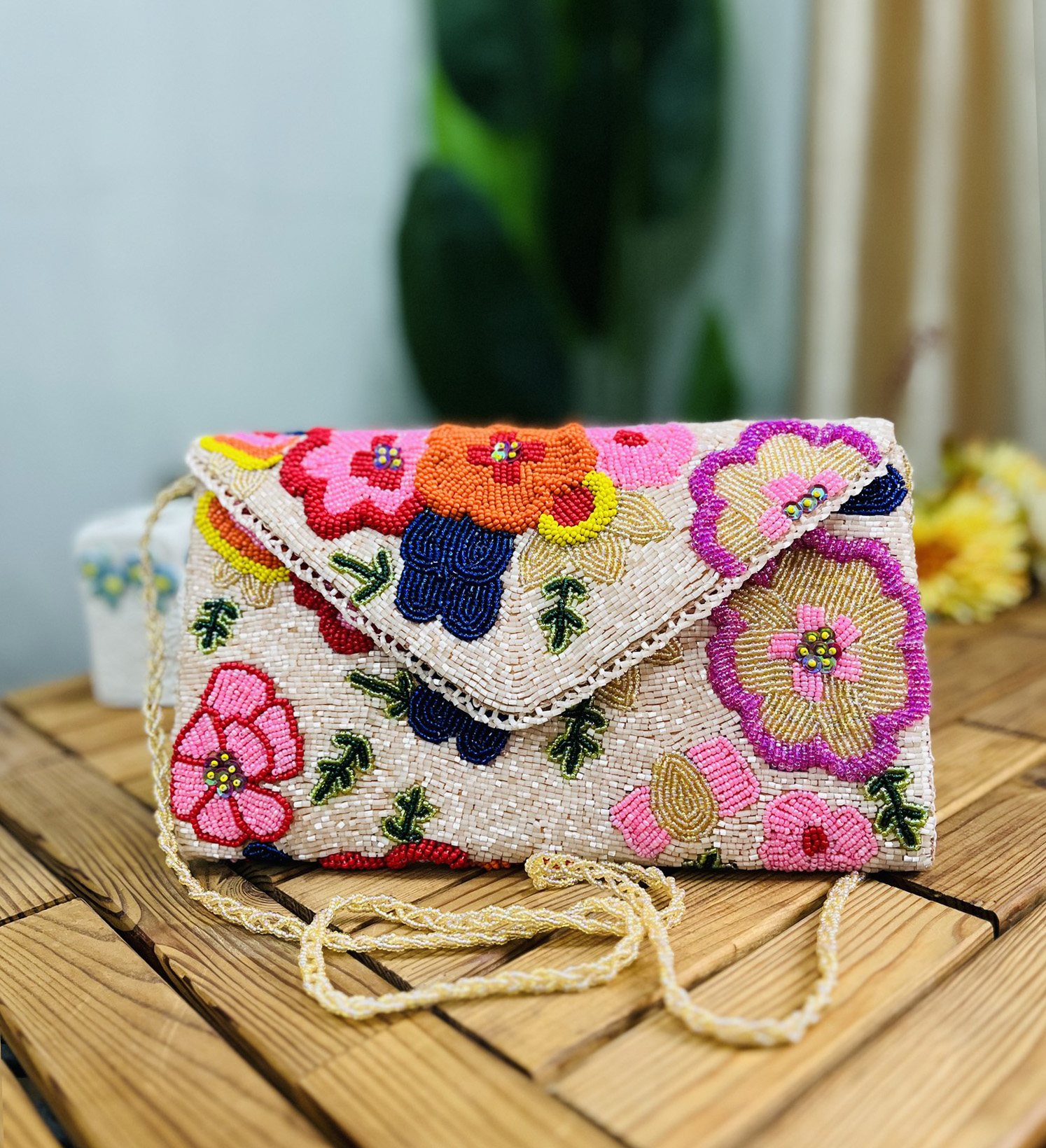 A colorful hand-beaded clutch with floral blossom patterns, made by Zara, on a white background.