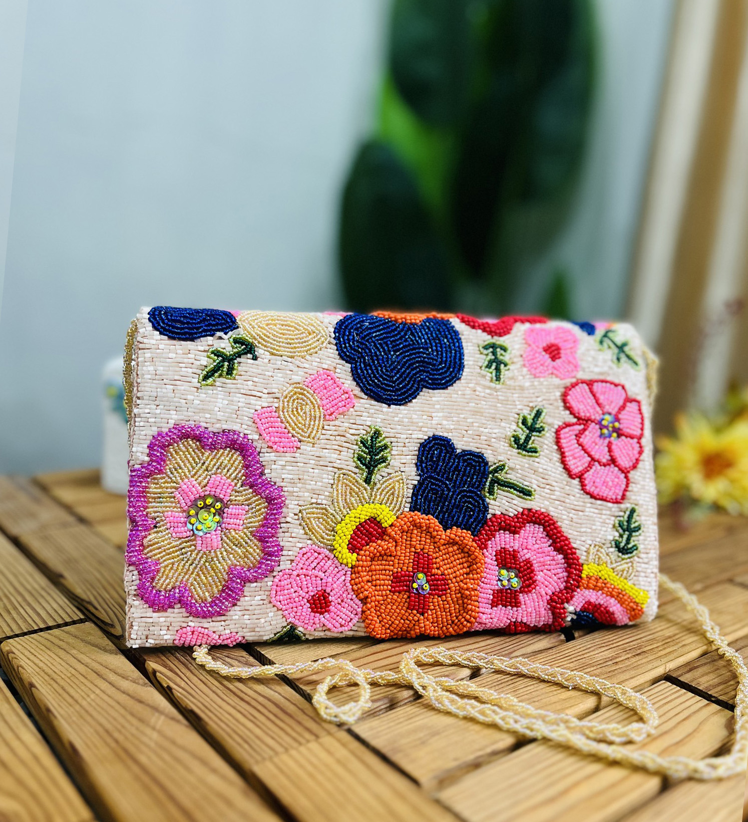 Hand-beaded envelope clutch with floral blossom design, vibrant beads, intricate patterns, tan background from Zara Label.