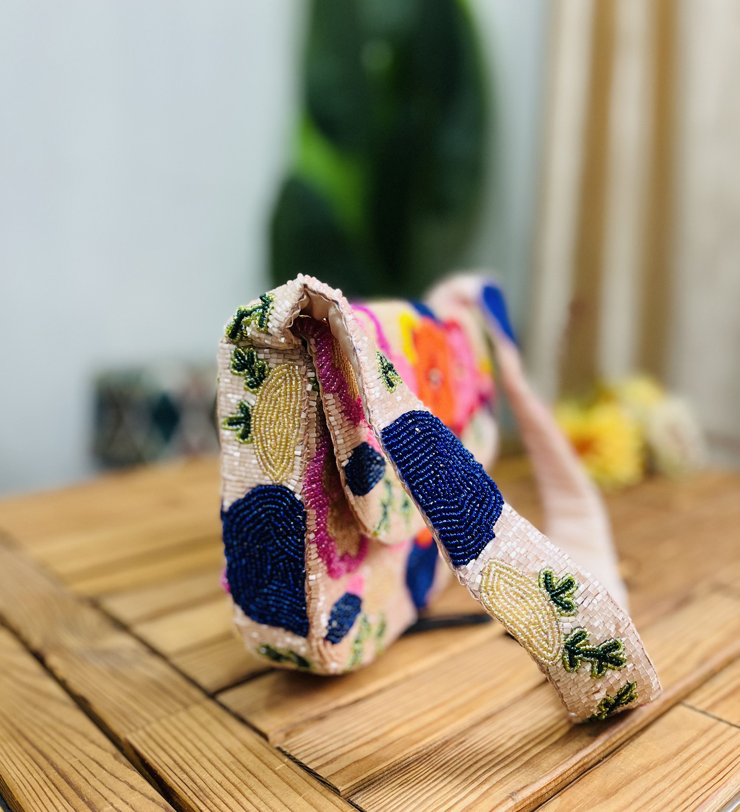 Hand-beaded shoulder bag with vibrant floral pattern on a dark background, designed by Zara Label, displayed on a neutral