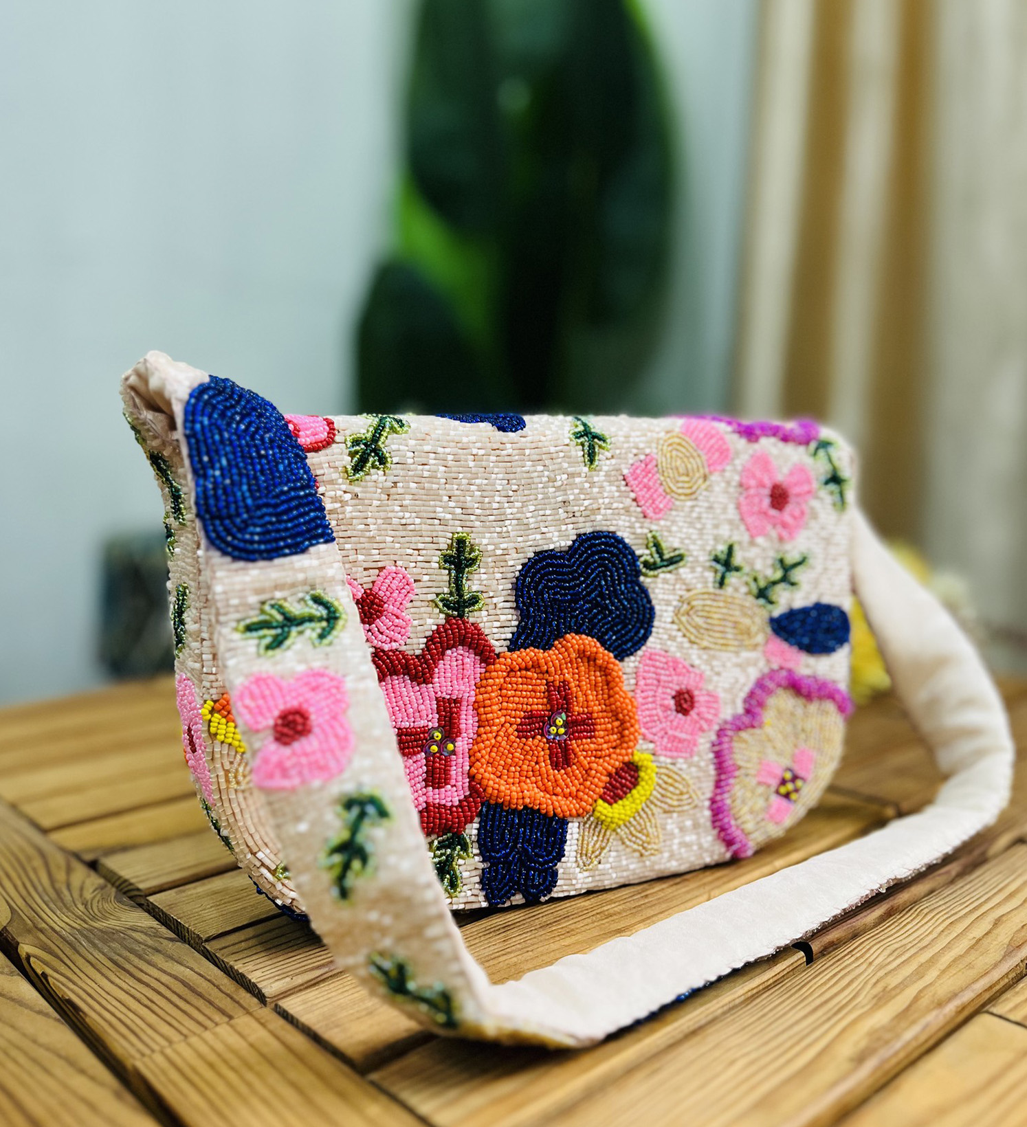 A colorful, hand-beaded shoulder bag featuring intricate floral designs, shown against a plain background, highlighting the