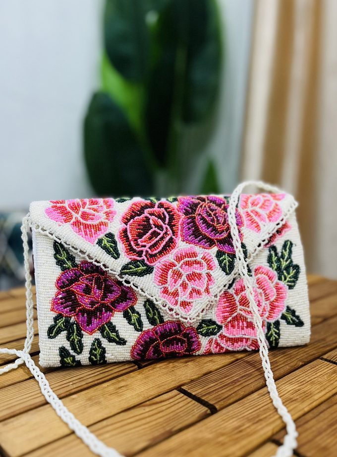 A vibrant envelope clutch adorned with intricate beaded floral rose patterns, showcasing the artisan craftsmanship of Zara