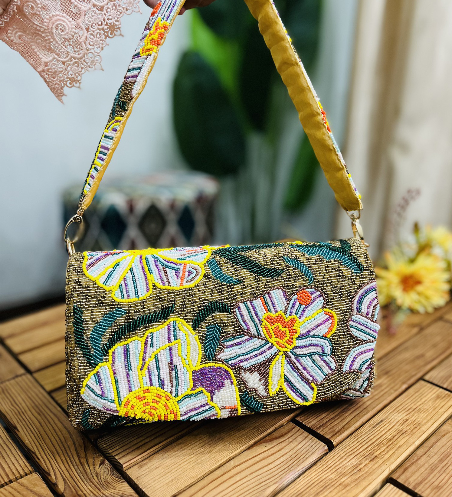 Gold shoulder bag with intricate floral beadwork, featuring a statement design, against a plain background.