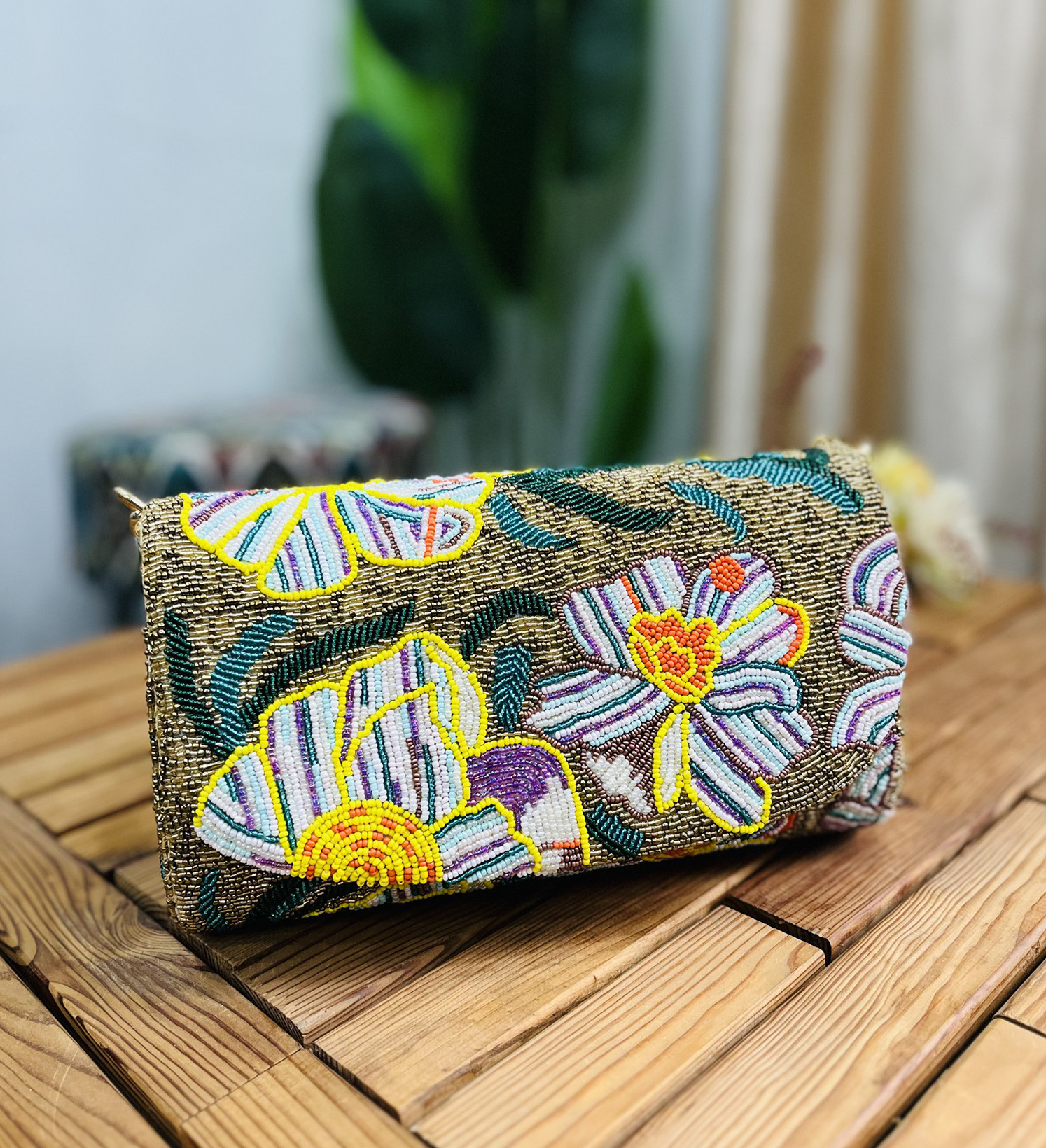 Gold shoulder bag adorned with intricate floral beadwork, featuring a statement design by Zara, displayed against a plain