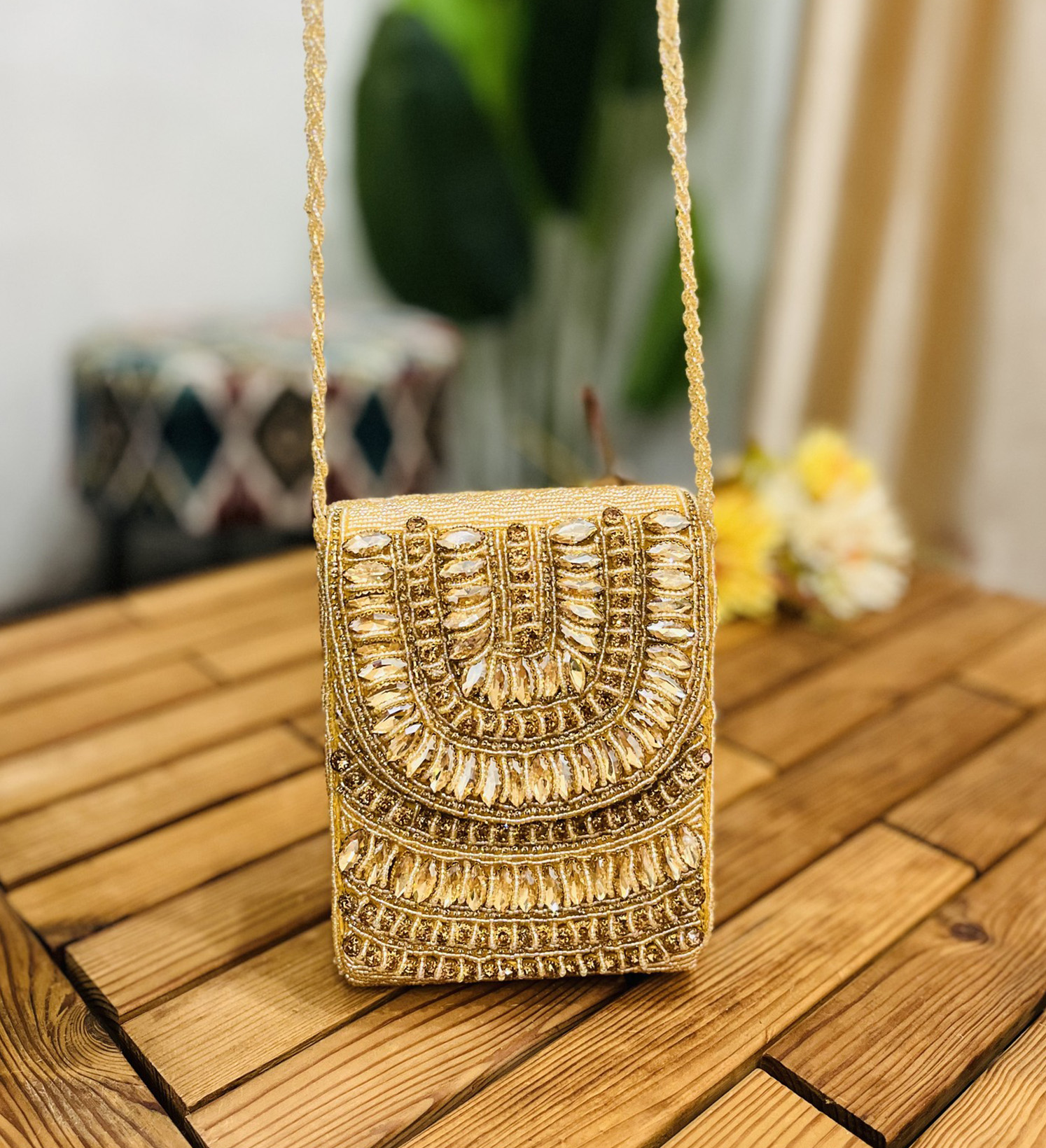 Golden crystal and beaded statement clutch with intricate design, featuring sparkling accents and elegant clasp, against