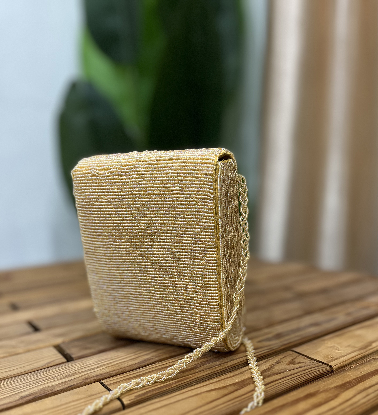 Golden crystal and beaded statement clutch with geometric design, featuring dazzling gemstones and intricate beadwork.