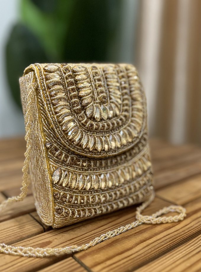 A vibrant golden clutch adorned with intricate crystal and bead designs, showcasing a detailed artisan craftsmanship from