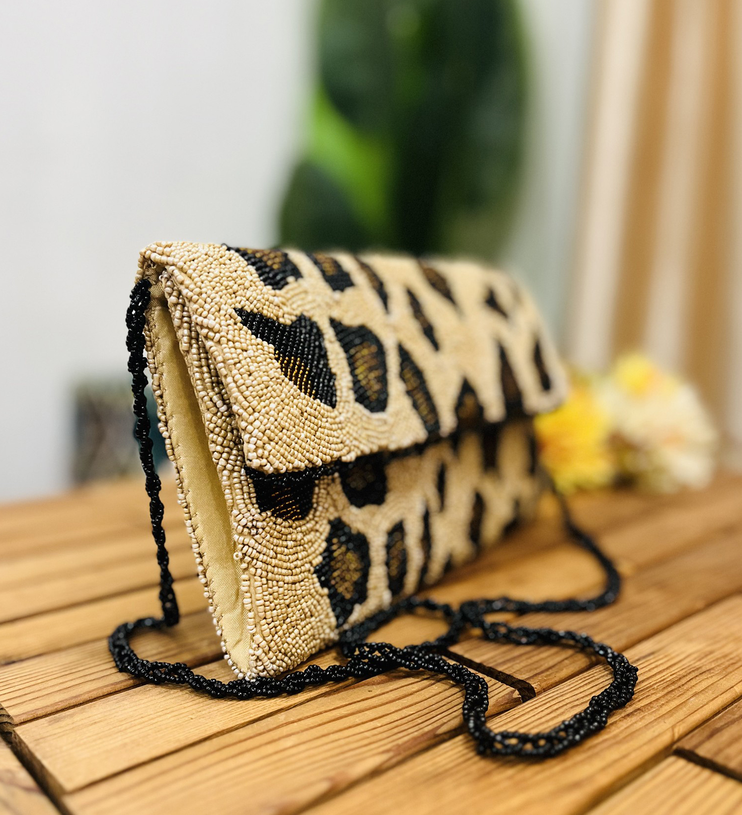 Leopard print hand-beaded envelope clutch with intricate design, showcasing natural earthy tones and a magnetic flap closure.
