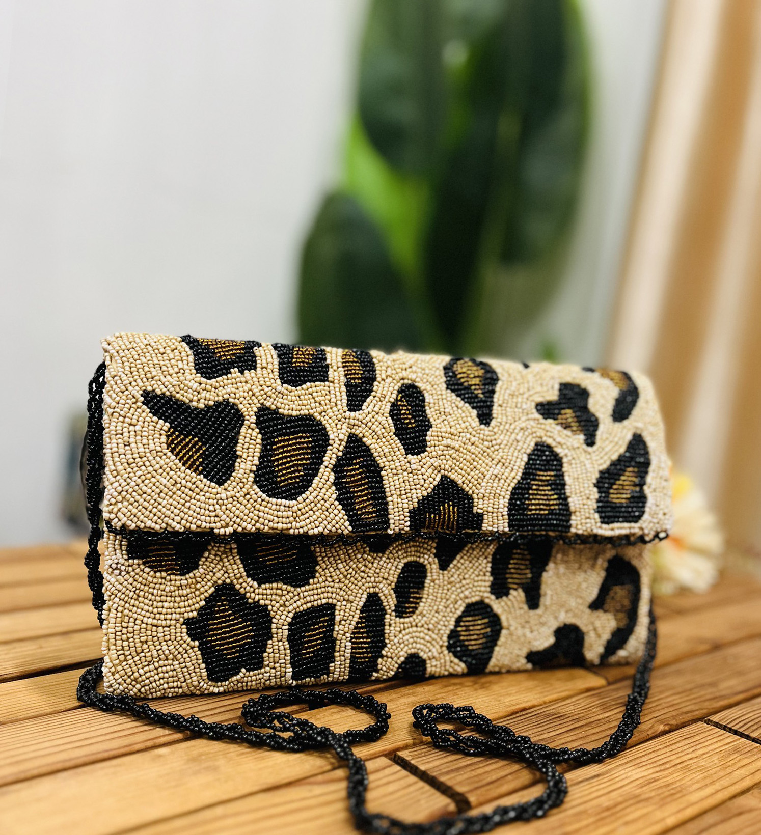 Artisan hand-beaded clutch with leopard print design, featuring a unique envelope shape and intricate bead detailing.