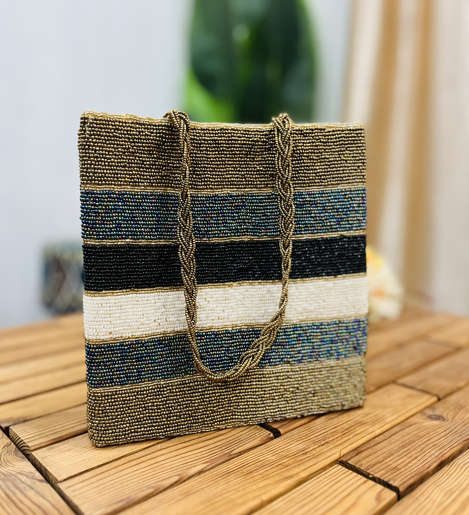 Colorful tote bag with metallic stripes, hand-beaded design, and beige handles, displayed on a plain white background.