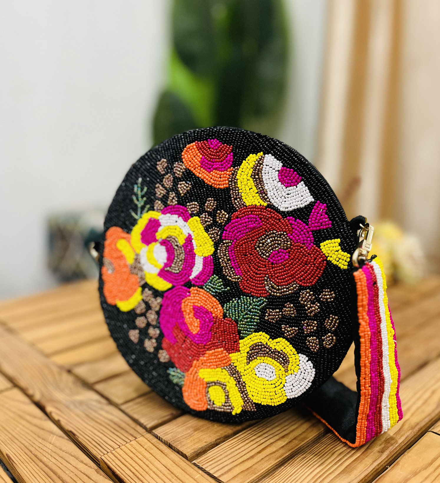 A circular hand-beaded shoulder bag with intricate floral designs in vibrant colors, on a neutral background.
