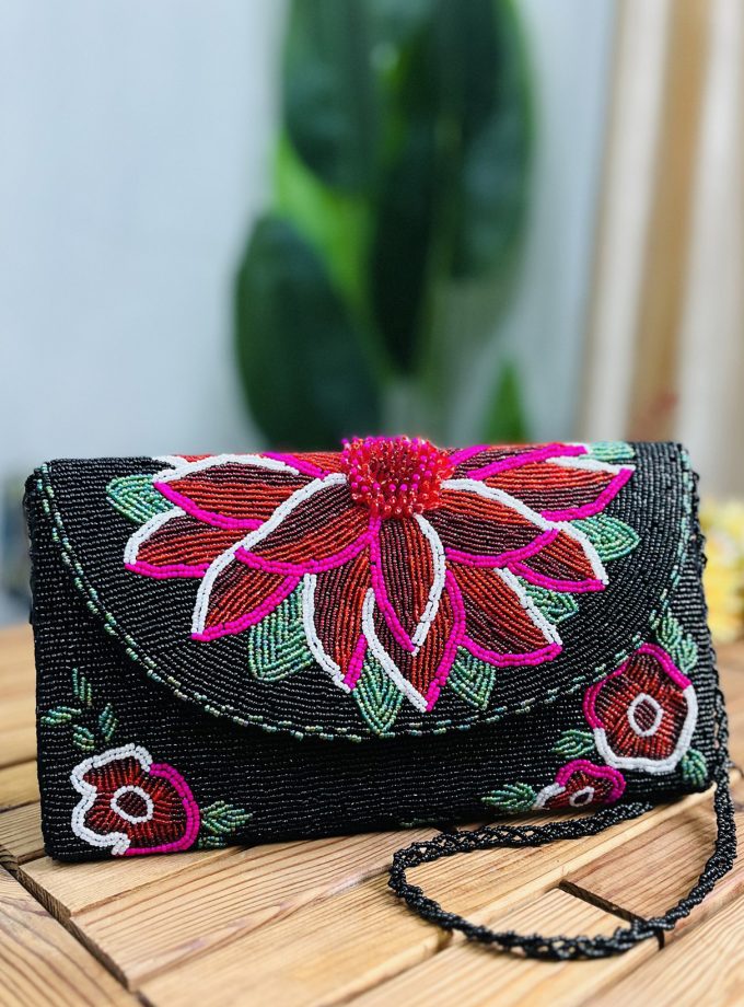 A sleek envelope clutch with intricate floral beadwork on a midnight blue fabric, designed by Zara Label, against a neutral