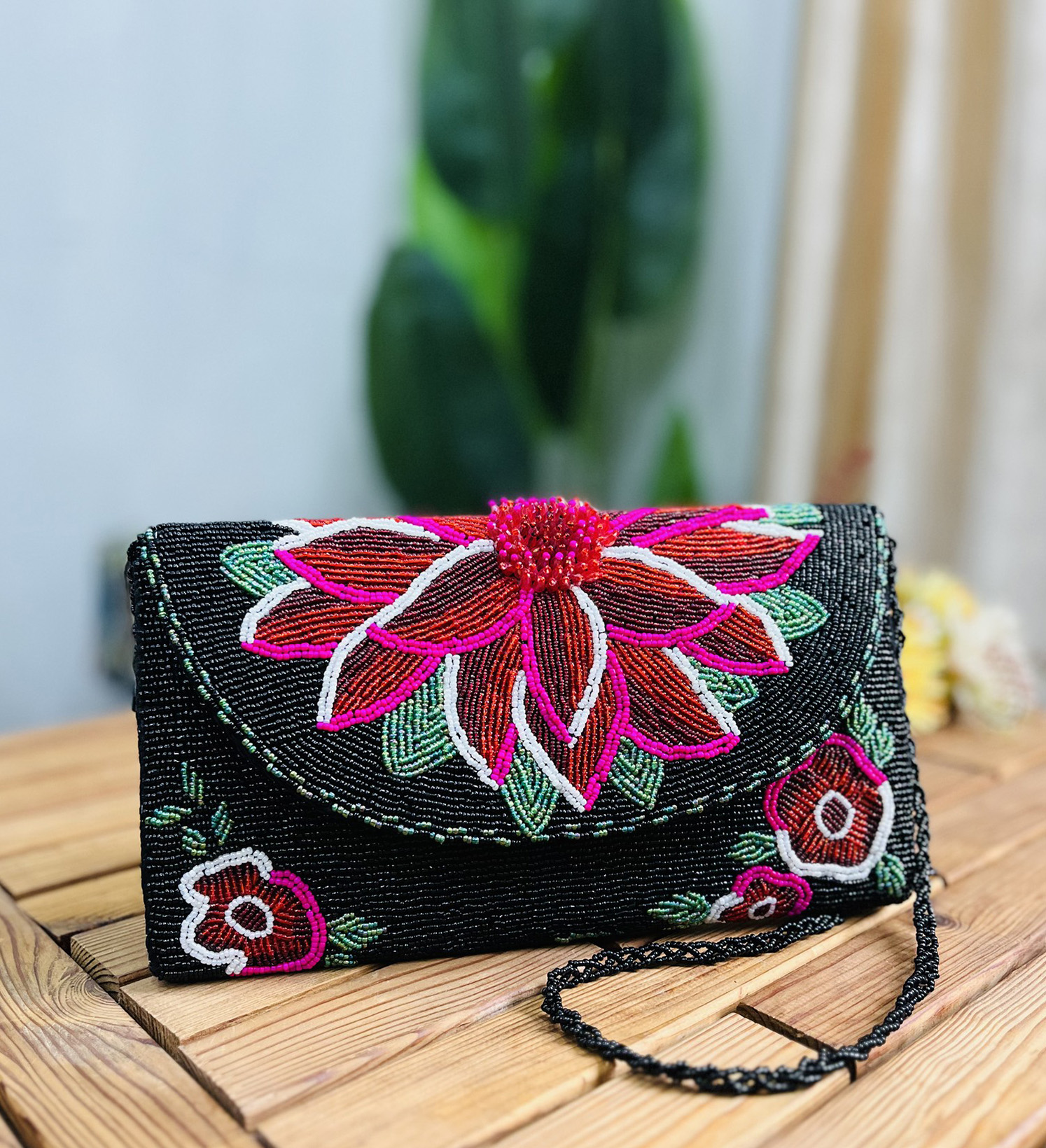 A sleek envelope clutch with intricate floral beadwork on a midnight blue fabric, designed by Zara Label, against a neutral