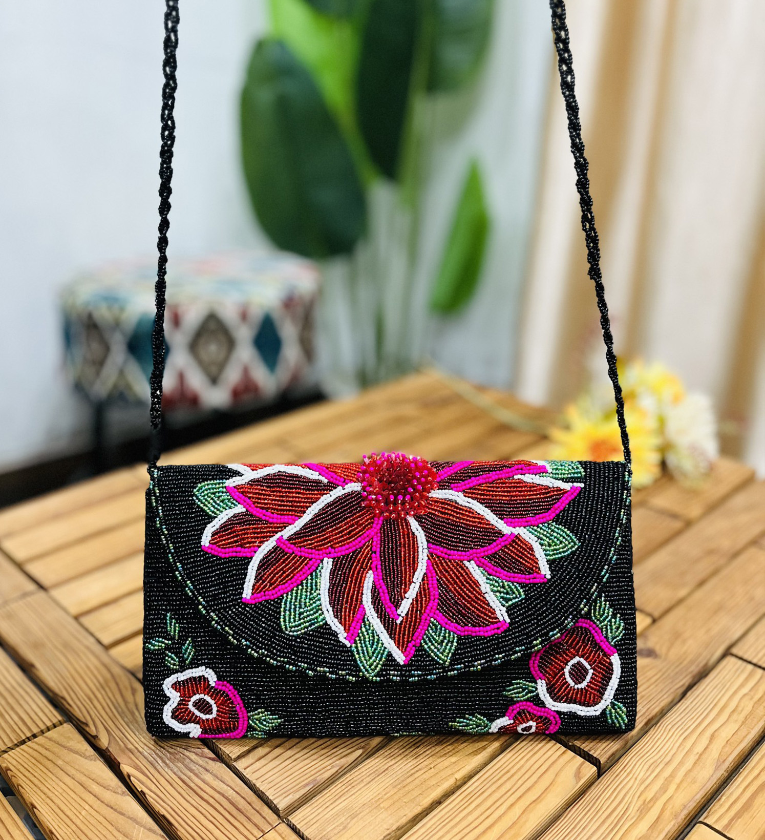 A clutch with intricate floral beadwork in vibrant colors on a midnight blue background, featuring a flap closure with a