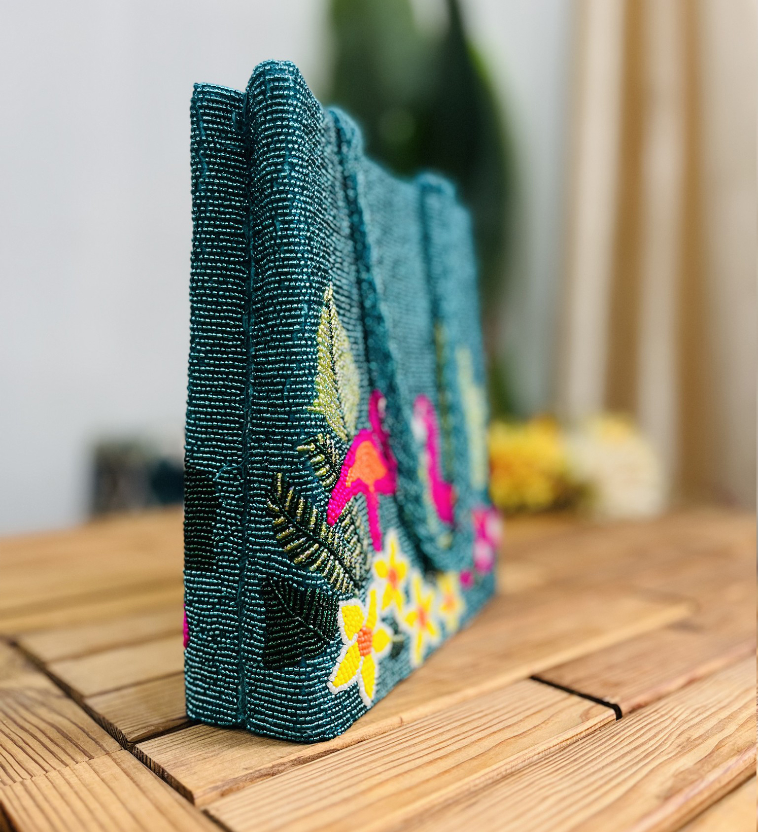 A colorful hand-beaded tote bag featuring vibrant pink flamingos and tropical greenery on a light fabric background.