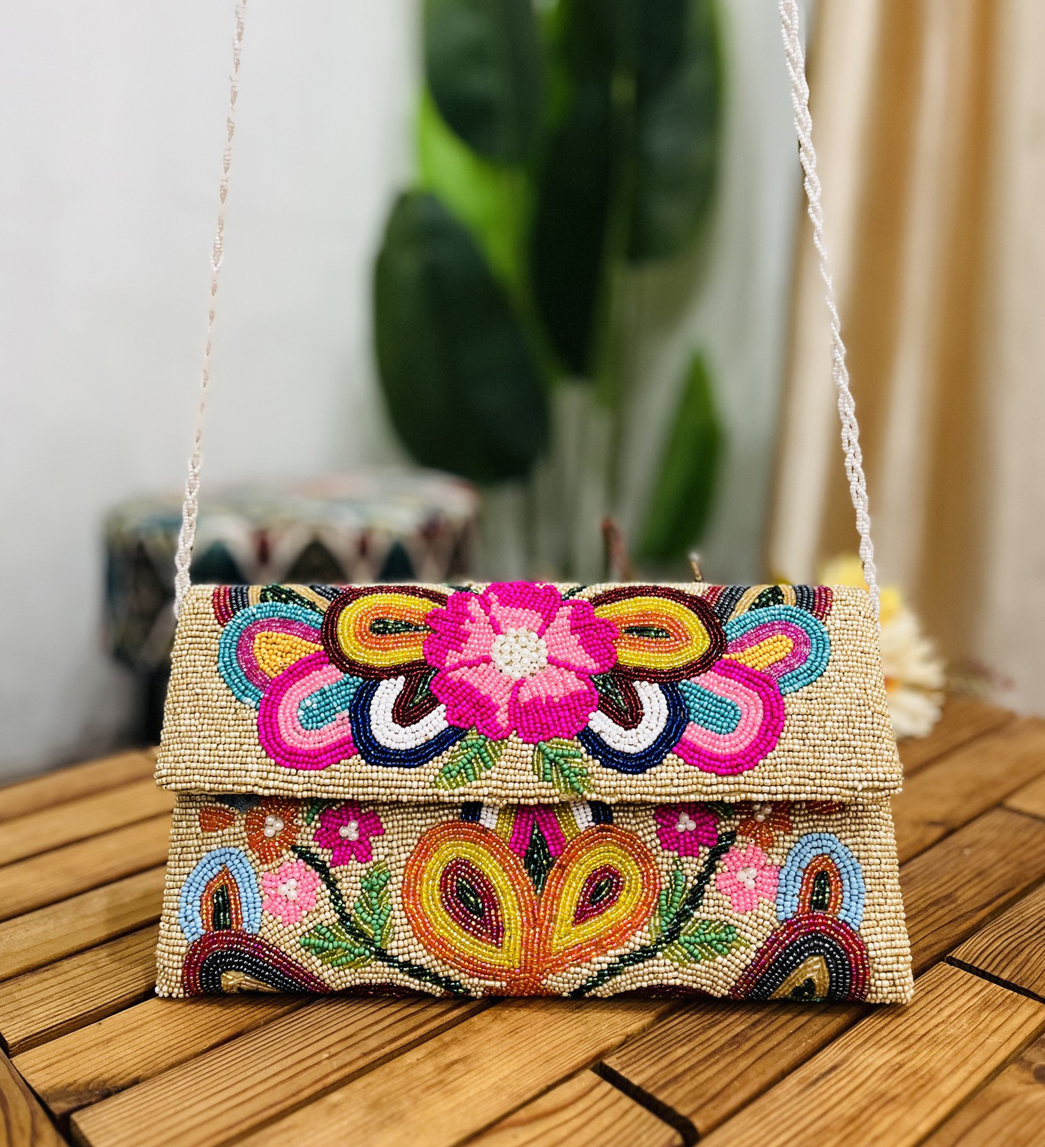 A colorful, hand-beaded envelope clutch with intricate floral patterns, marked with a Zara label, displayed against a