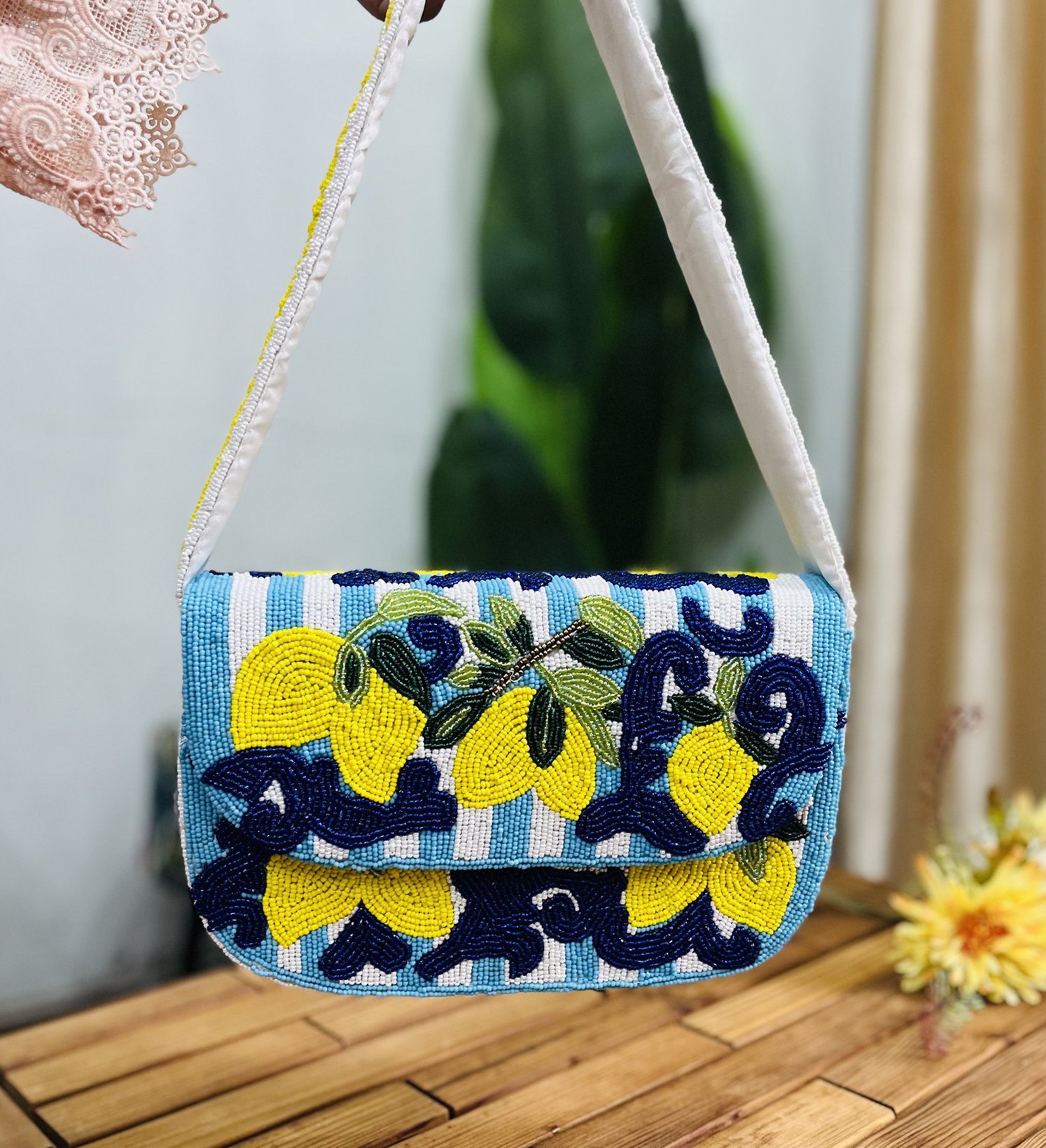 A rectangular shoulder bag beaded with lemon motifs on a white background, featuring a chain strap and a zip closure.